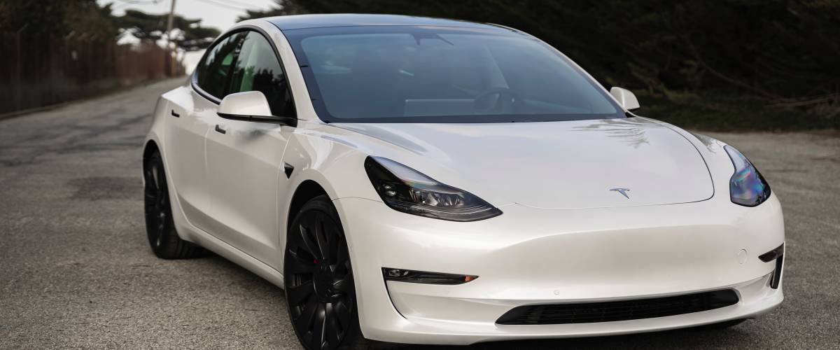 Pearl white electric Tesla Model 3 dual motor performance AWD car with 20 inch Uberturbine wheels.