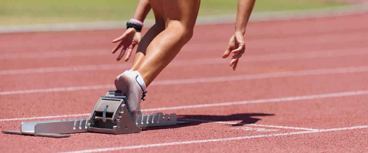 Athlete female feet on starting block ready for a sprint start