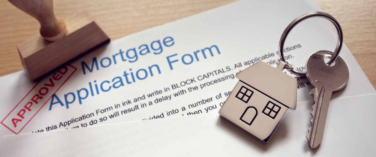 Mortgage loan agreement application with key on house shaped keyring