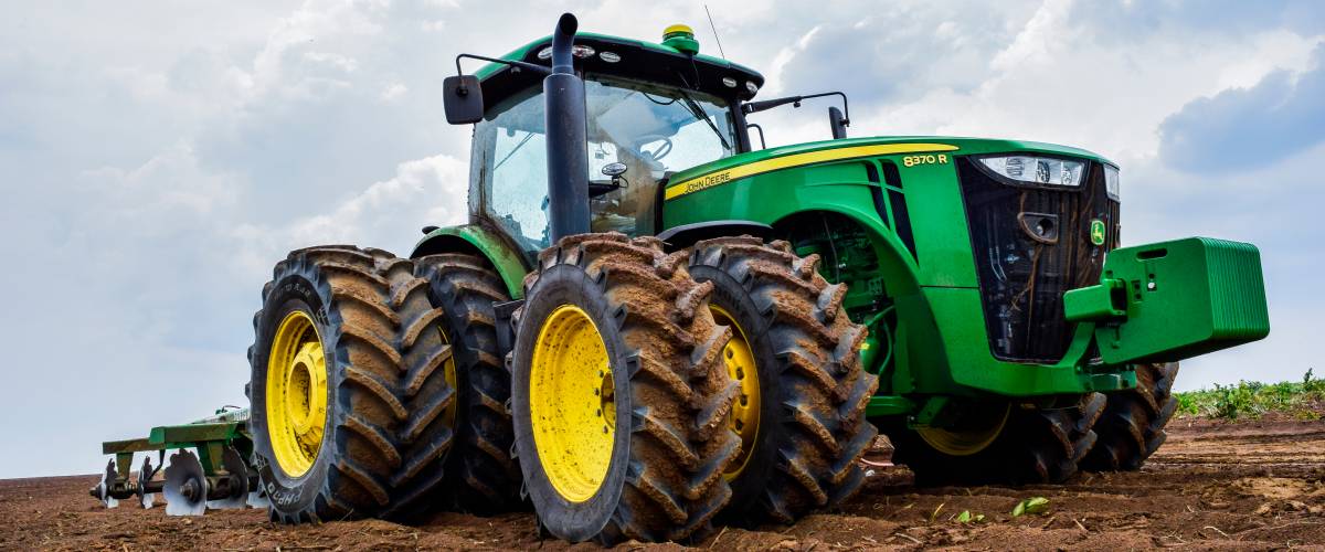 Tractor 8R John Deere plowing the earth.