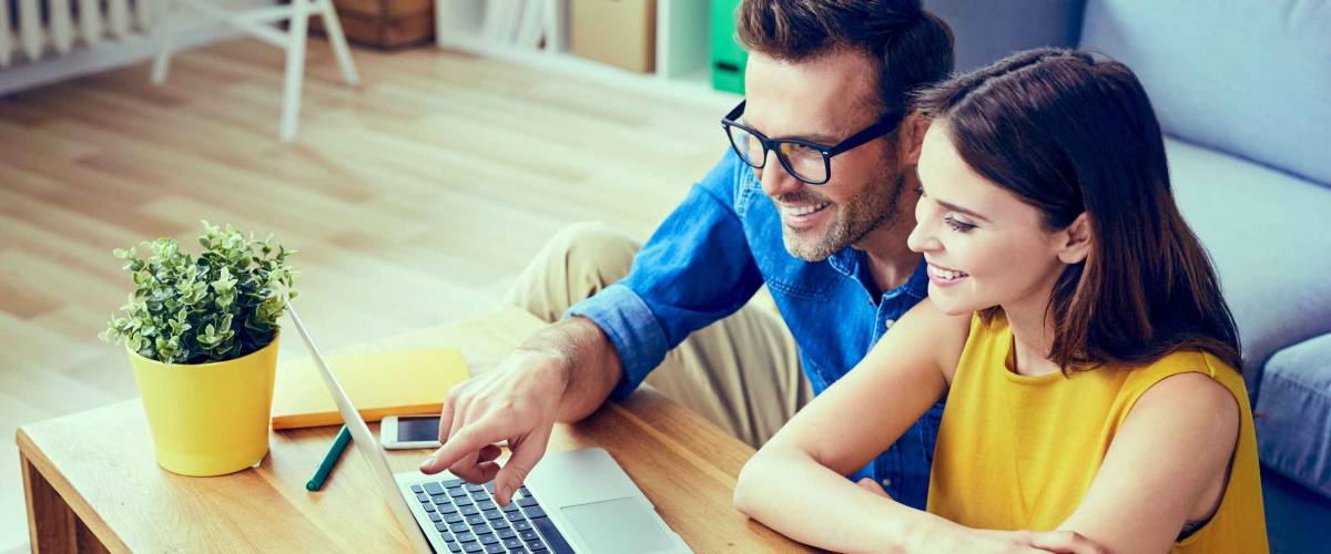 Happy couple with laptop spending time together at home