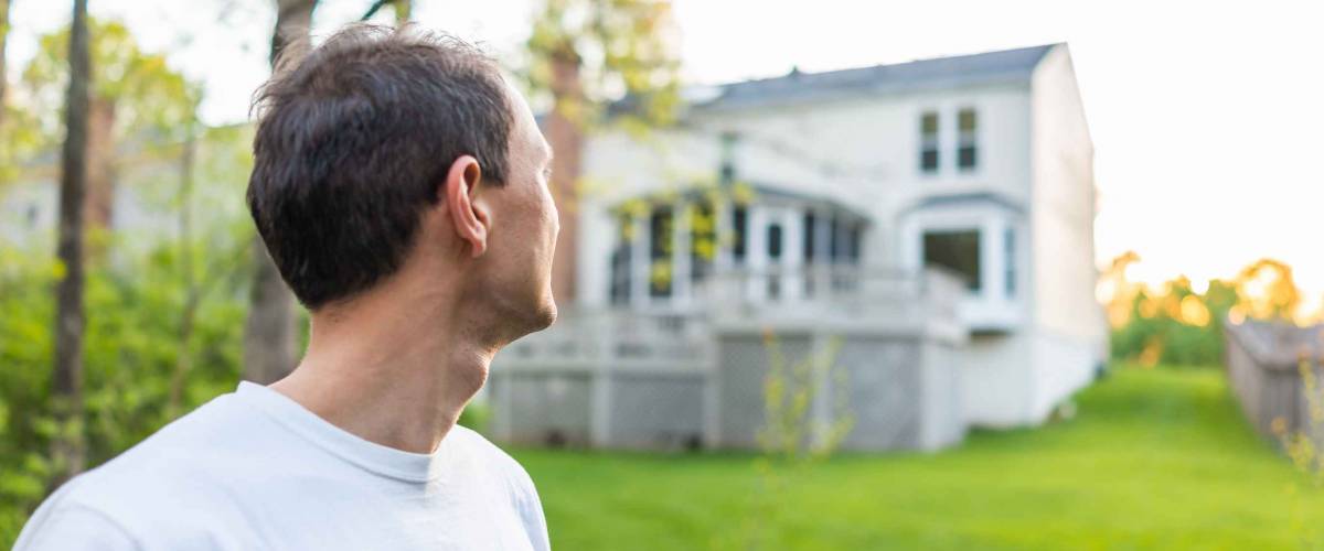 Young man homeowner in Herndon, Northern Virginia, Fairfax county residential neighborhood in spring or summer looking at house backyard