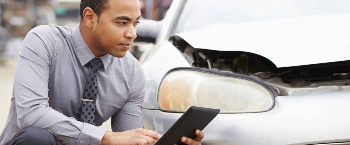 Loss Adjuster Using Digital Tablet In Car Wreck Inspection