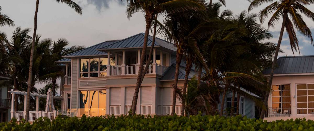 Coast house beachfront waterfront vacation home, house during evening sunset with nobody in Florida, gulf of mexico, storm weather and wind palm trees