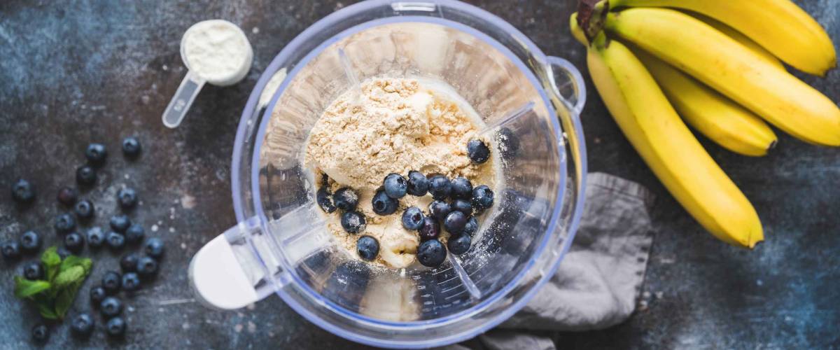 Blueberry protein powder in blender, smoothie preparation, top view. Concept of fitness healthy eating, clean eating, sport lifestyle