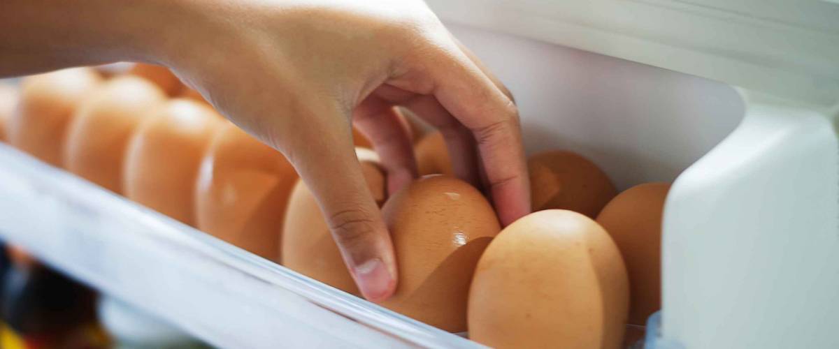 Pick chicken egg from the refrigerator, eggs on shelf of refrigerator