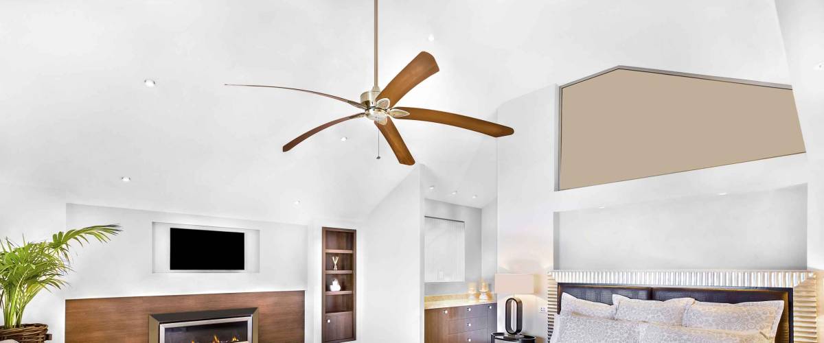 Modern bed area including furniture, television is attached to wall, one chair close to flower pot, fan can see on ceiling, lamp table near wall, perfect lights balancing, very clean area.