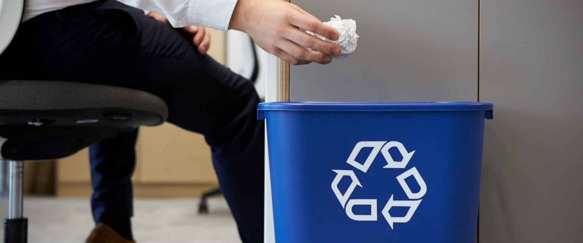 Man dropping screwed up paper into recycling bin, close up