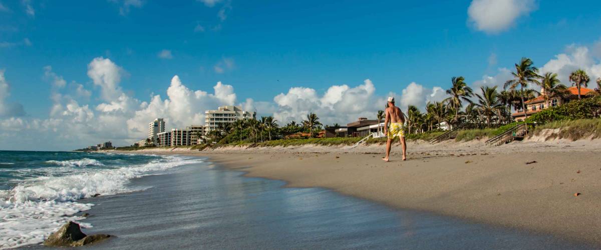 Unidentifiable senior man briskly walking on beautiful beach in Jupiter Hobe Sound area of Florida