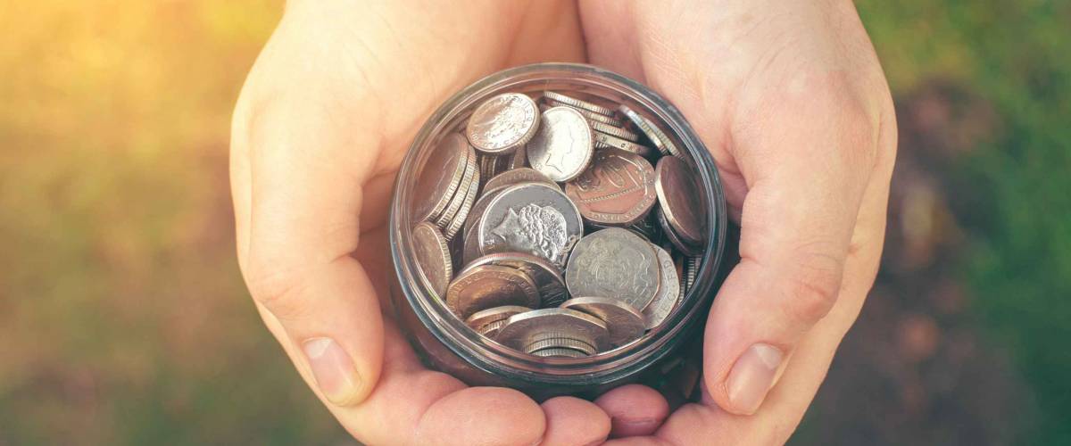 Man's hands hold a glass jar with a coins (toned, save money concept)