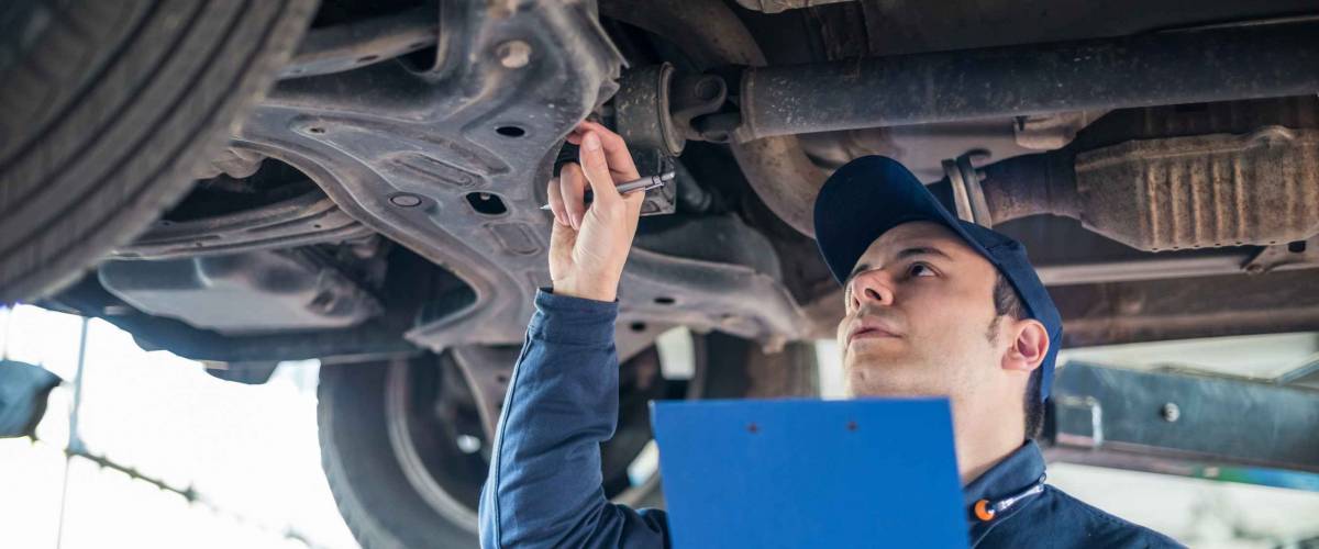 Portrait of a mechanic inspecting the underside of a car.