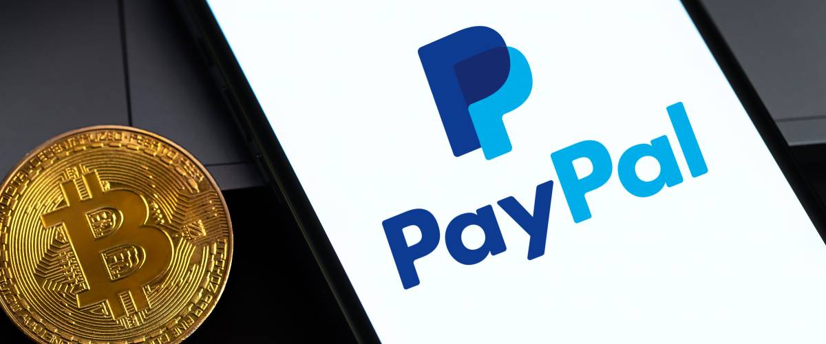 PayPal logo on the screen iPhone with bitcoin cryptocurrency in the dark.