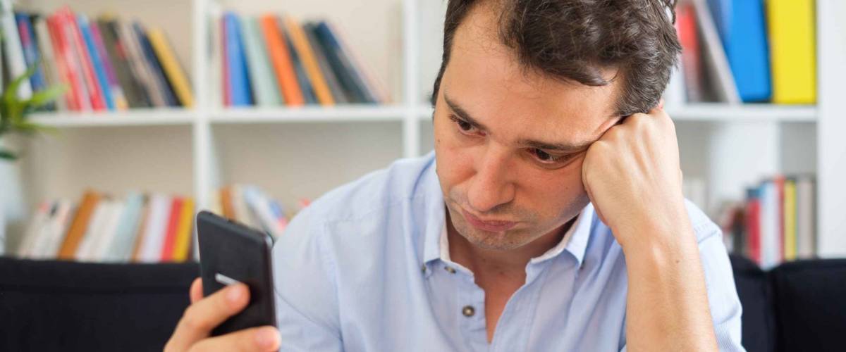 Sad man waiting for a message and watching mobile phone display