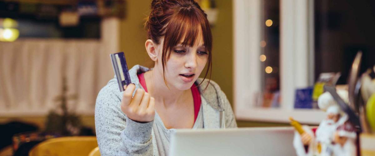 Young Woman at Computer stressed with a credit card