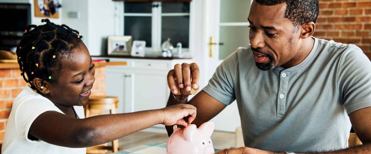 Dad and daughter saving money to piggy bank