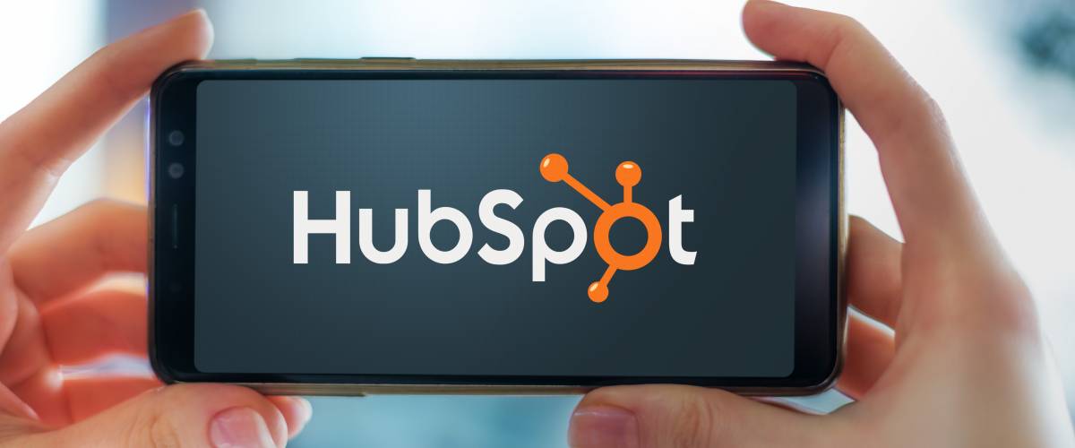 Hands holding smartphone displaying logo of HubSpot, an American developer and marketer of software products for inbound marketing, sales, and customer service