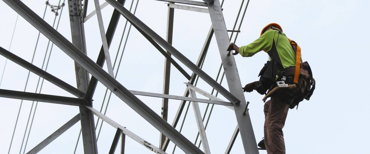 worker climbing on transmission line tower