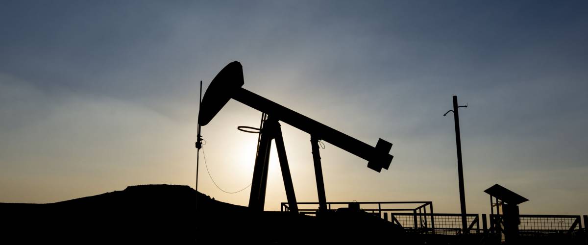 Silhouette of crude oil pump in oil field at sunset