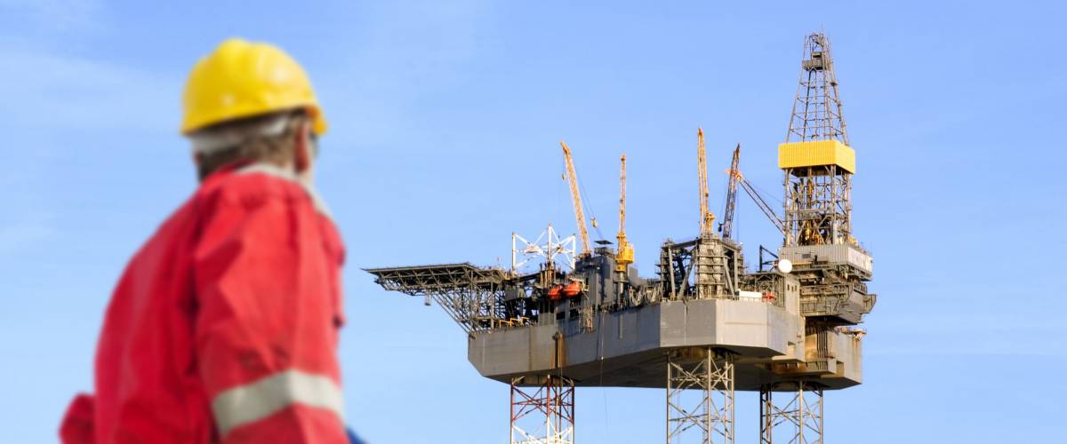 Roughneck (out of focus) looking at a huge oil rig being constructed.