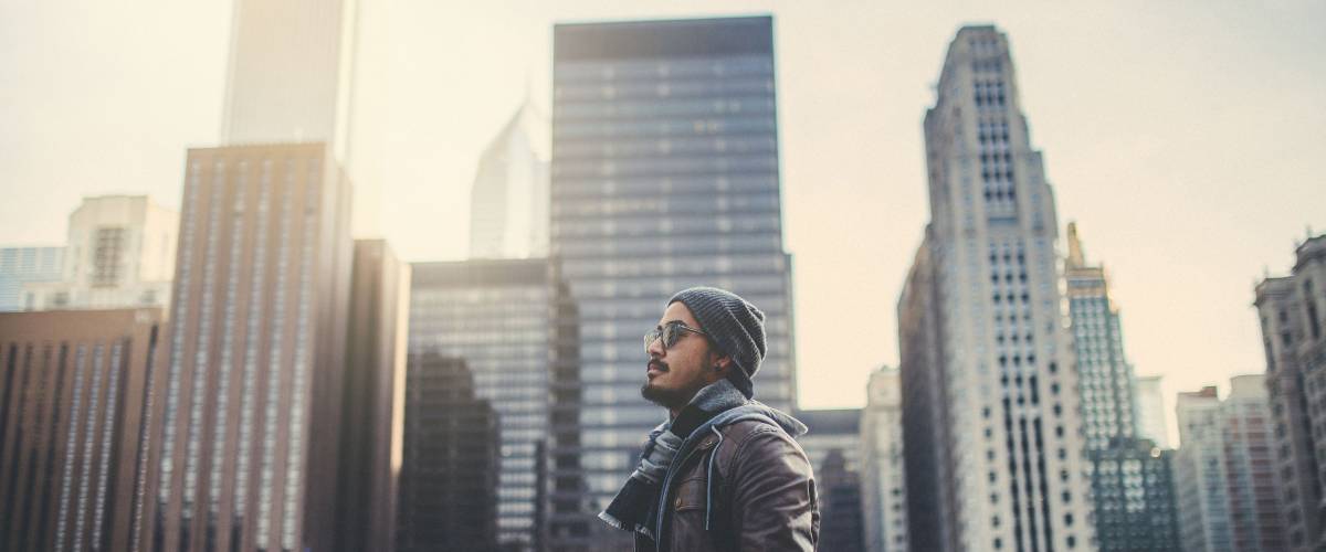 A young man standing with beautiful buildings background before sunset at Chicago city : films grain concept