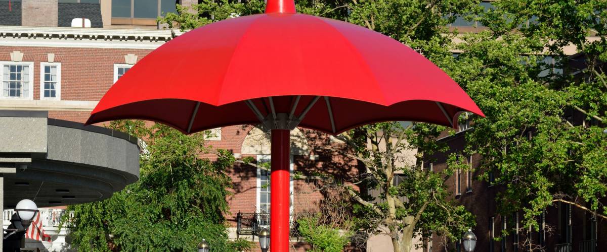 HARTFORD, CT - JUNE 20, 2017: A large red umbrella is with a group of people walking in the courtyard of the Travelers Companies offices.