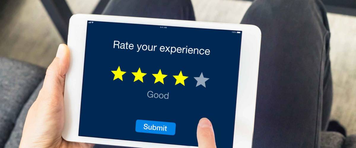 Person using digital tablet computer at home to send customer rating with online website, satisfaction review based on star icons, concept about quality management