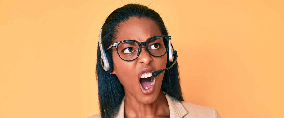 Young african american woman wearing call center agent headset angry and mad screaming frustrated and furious, shouting with anger. rage and aggressive concept.