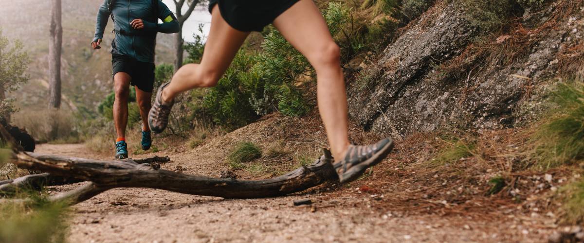 Woman's legs running up hill, man following behind