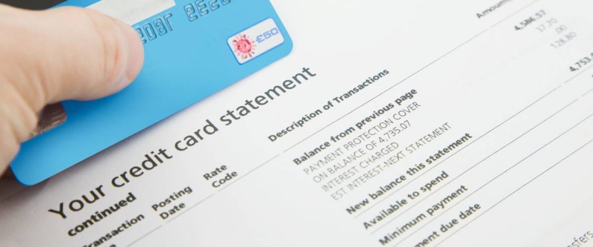 A credit card statement with a hand holding a blue credit card