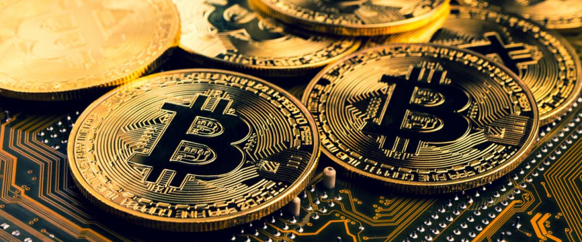 Golden coins with bitcoin symbol on a mainboard.