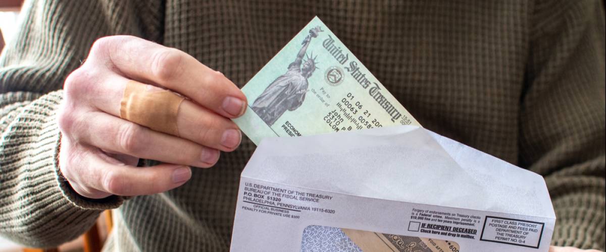 A man pulling his stimulus check out of the envelope