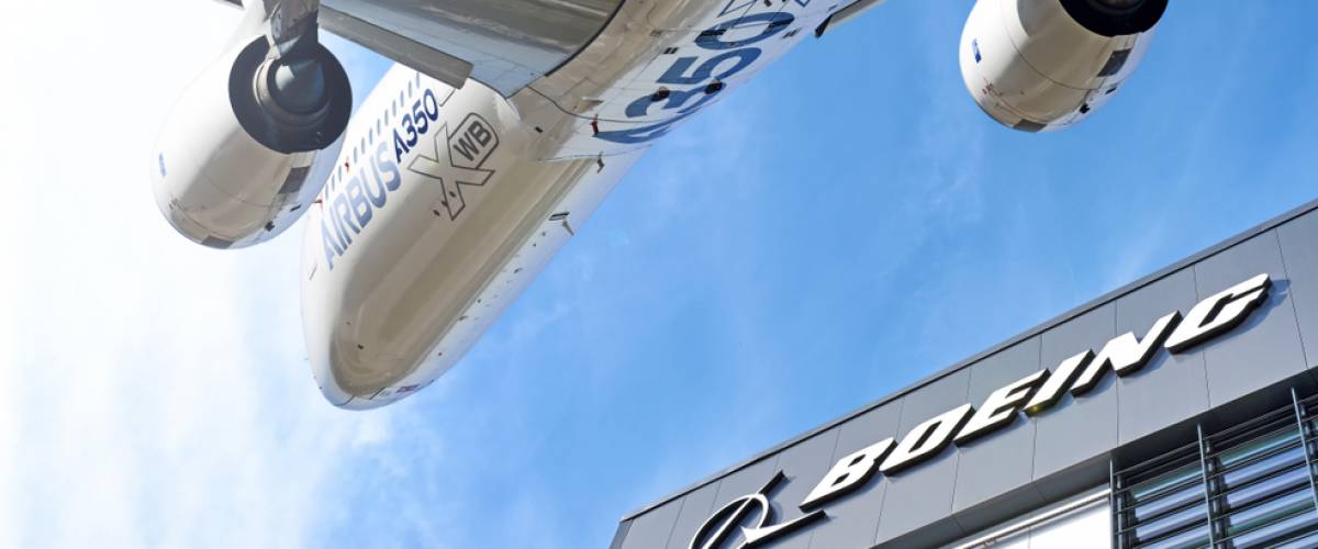 Boeing company lettering logo against Airbus A350 modern airplane flying on blue sky background wide view usa europe competition trade war concept