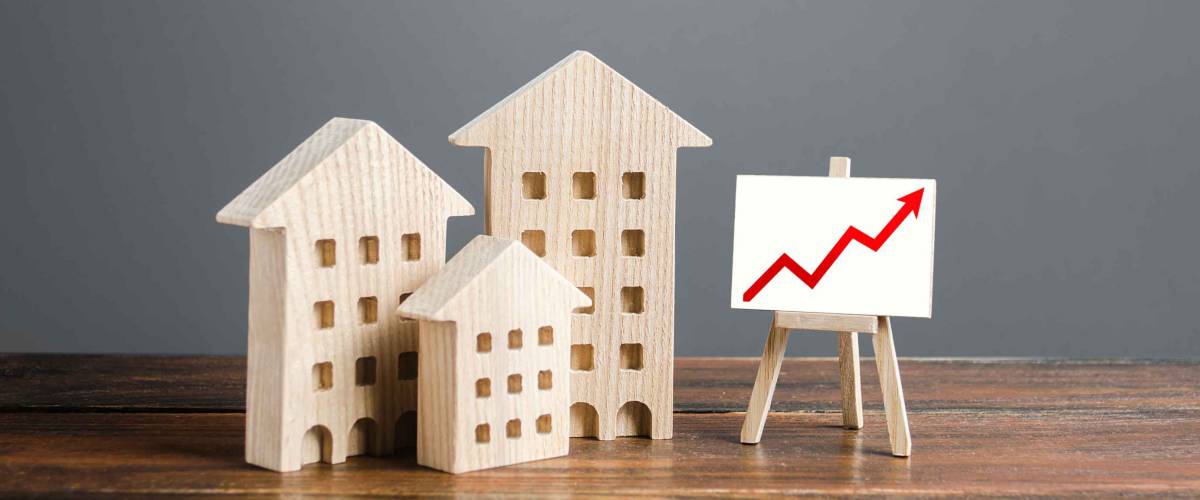 Residential buildings and easel with a positive growth trend red arrow up chart. Rising interest rates.
