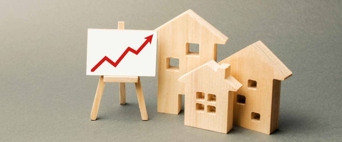 three wooden houses and a red up arrow on the sign. Real estate value increase. High rates of construction, high liquidity. Supply and demand. Rising prices for housing, building maintenance.