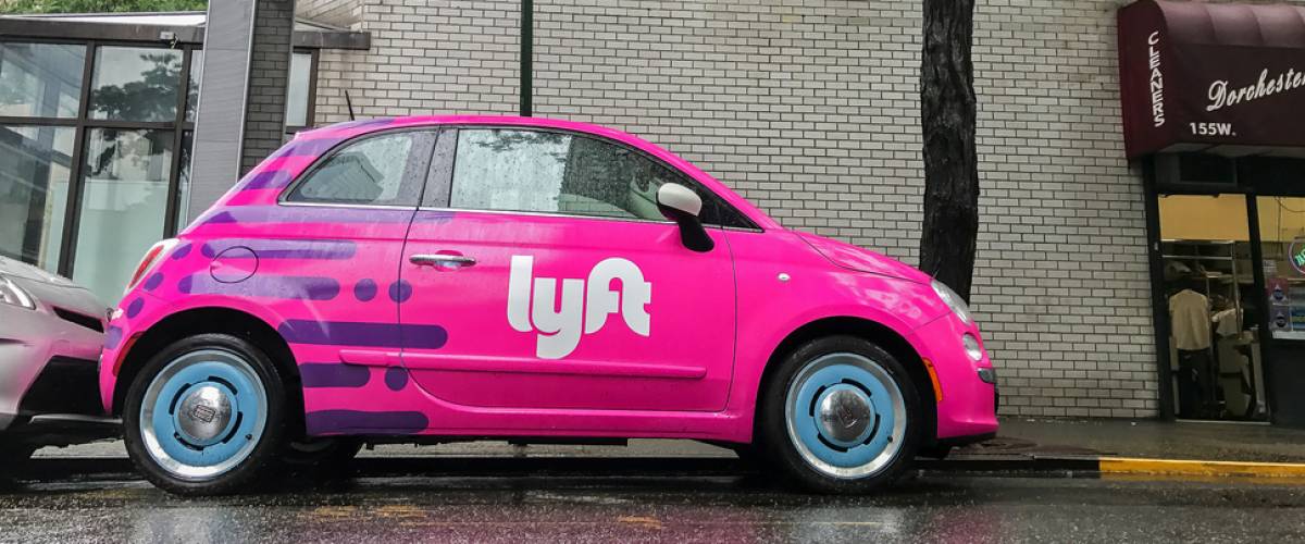 Fiat 500 painted pink and carrying a Lyft logo is parked in the streets of Manhattan.