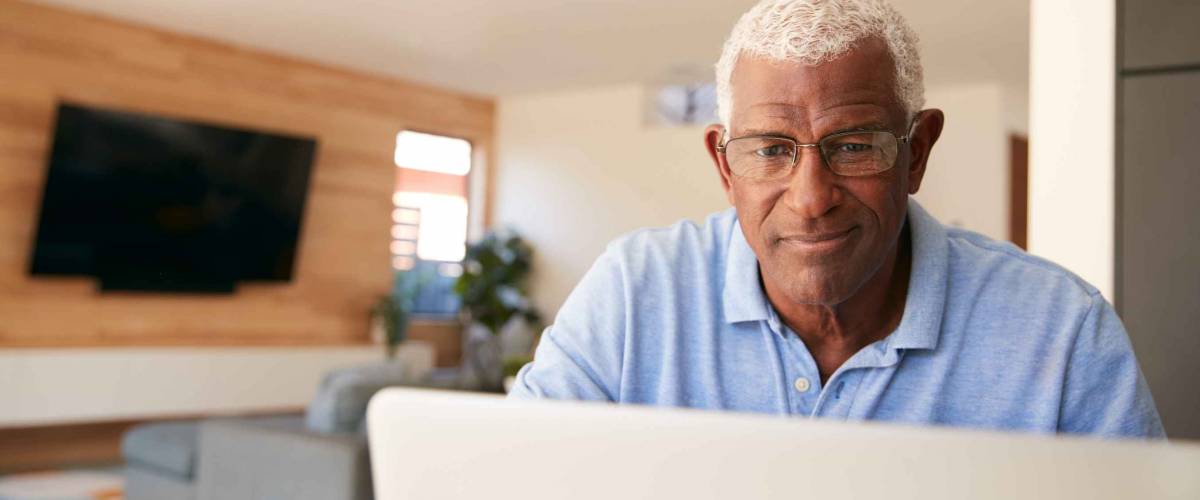 Senior African American Man Using Laptop To Check Finances At Home