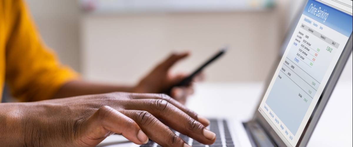 Closeup of a hands typing on a laptop and holding a cell phone