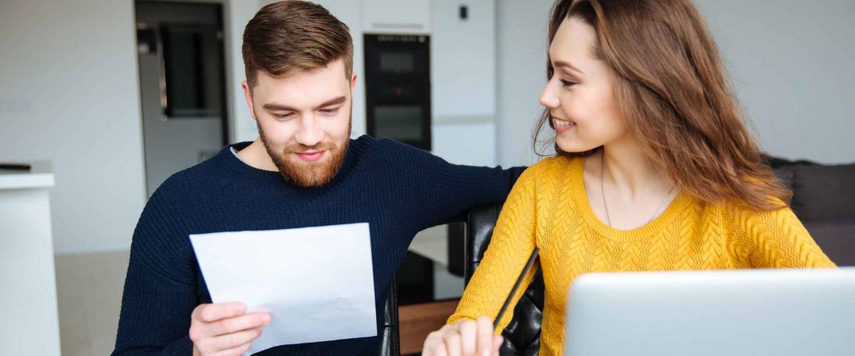 Happy young couple calculating bills at home