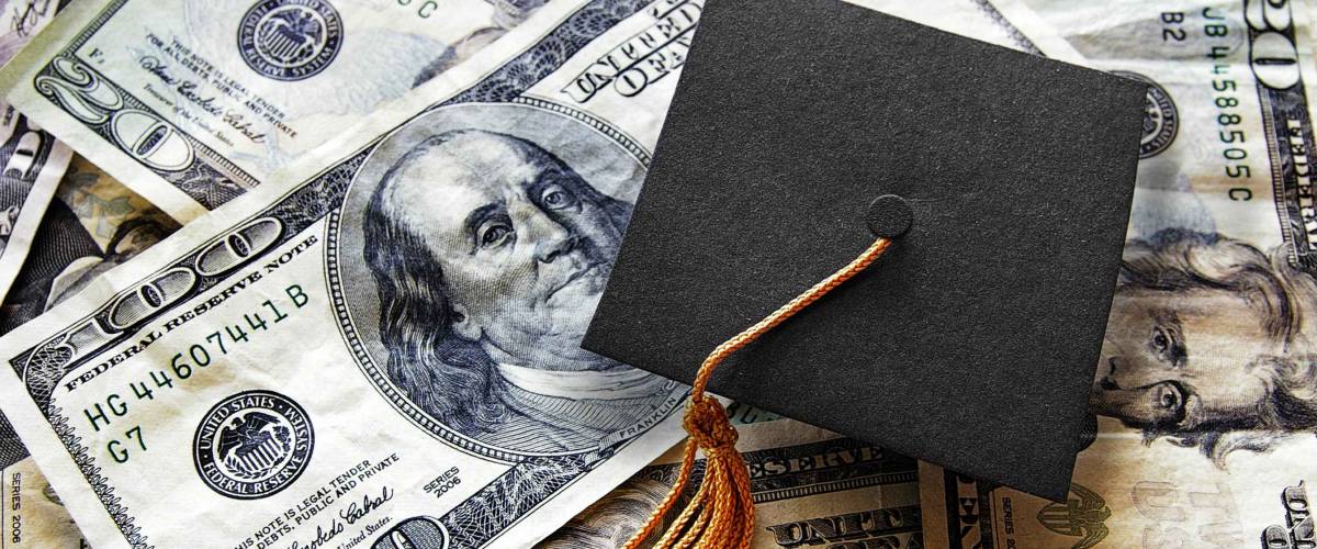 Miniature graduation cap on hundred dollar bills