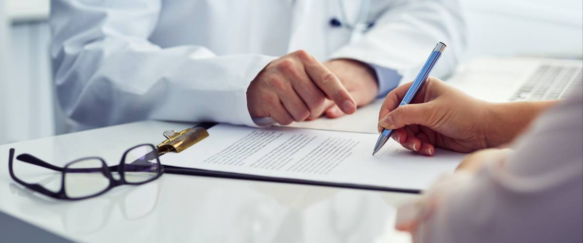 Female patient in office filling out medical document with doctor