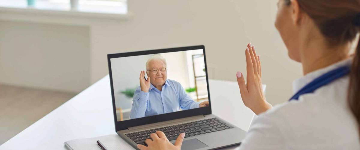 Smiling senior aged man patient greeting professional woman doctor online