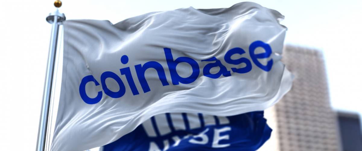 Flags of Coinbase and NYSE flying in the wind. On April 14, 2021, Coinbase went public on the Nasdaq exchange.