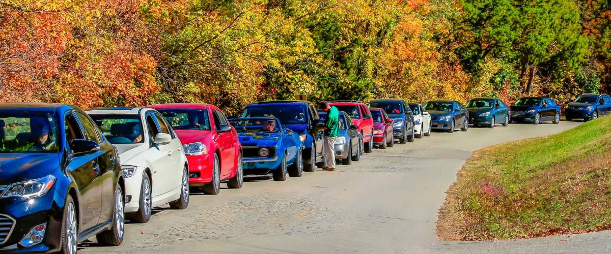 Long line of cars parked along the road in autumn