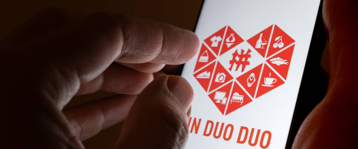 PinDuoDuo company logo on the smartphone hold in hands.