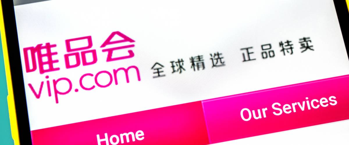 Vipshop Holdings website homepage. Vipshop Holdings logo visible on the phone screen.