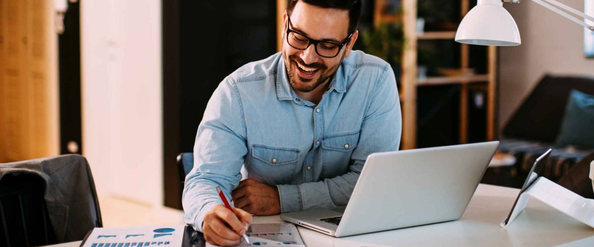 Young business man working at home with laptop and papers on desk