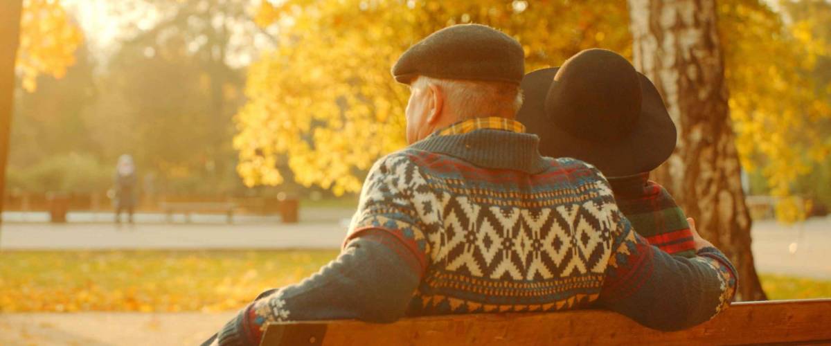 Senior couple enjoying sunset on the bench in the autumn park