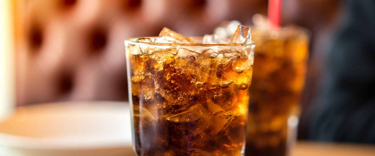 Double cool ice soft drink cola carbonated liquid fresh food with soda water, white dish on wooden table with handsome man sitting brown sofa in pizzeria restaurant.