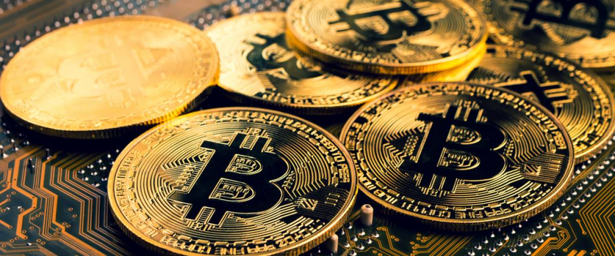 Golden coins with bitcoin symbol on a mainboard.
