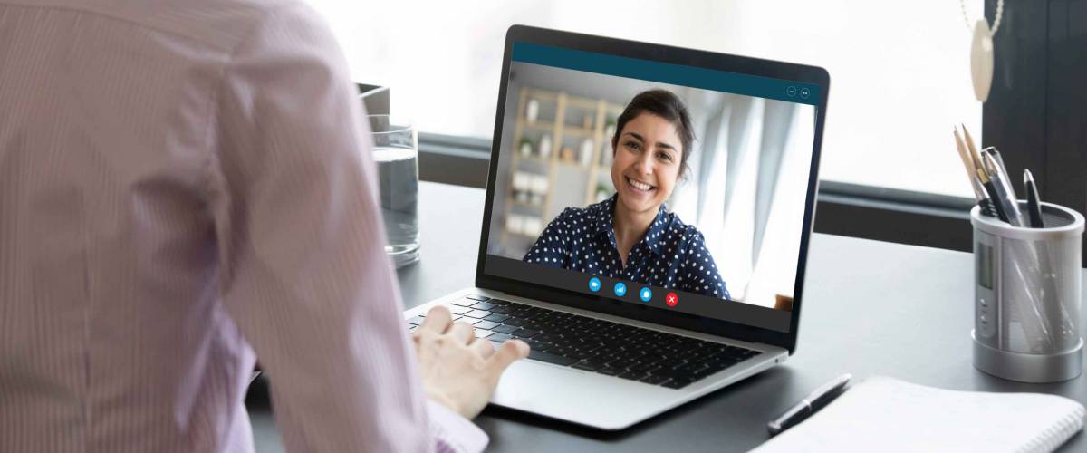 Indian girl communicate with friend on-line by video call, pc screen view over female shoulder.